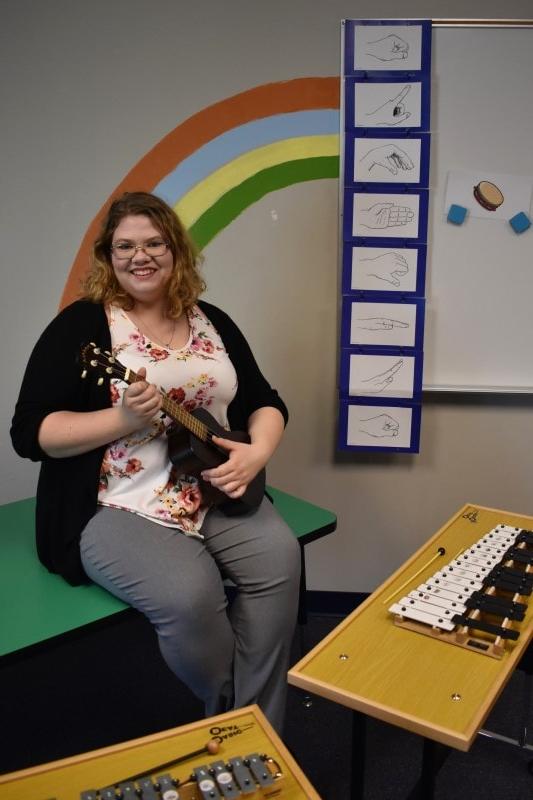 woman holding ukulele in a music room